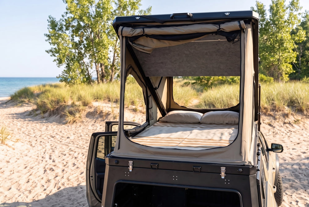 Rear view of the Chevy Colorado truck cap camper with the large rear tent window open and the bed made, on a Lake Huron beach