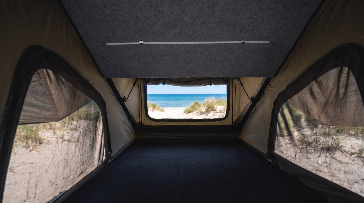 Inside the Double Pop-Up roof tent with bug-mesh windows on both sides and a beach view through the end window