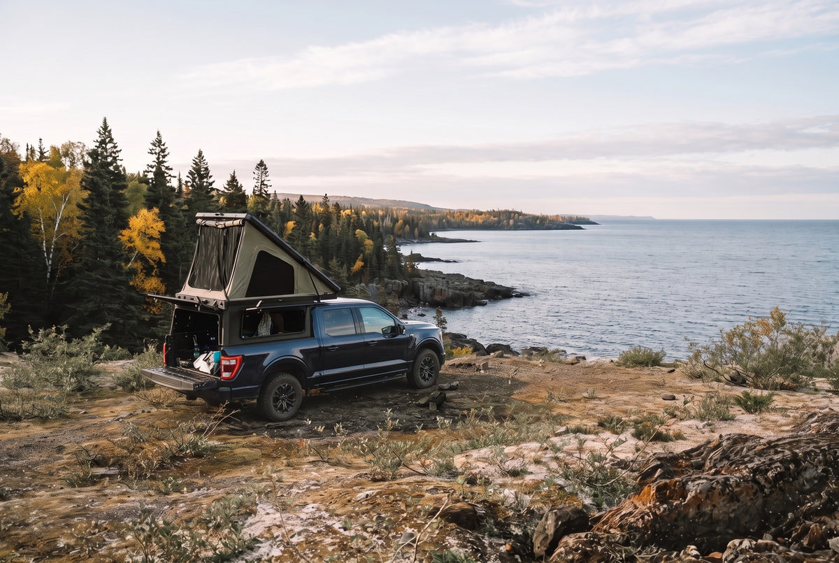 Wide view of a Ford F-150 truck camper set up above the Lake Superior shoreline in autumn