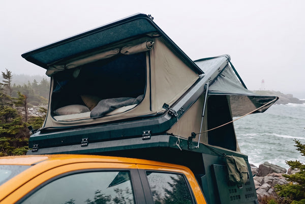 Ford Maverick pop-up truck camper with the roof tent open at camp