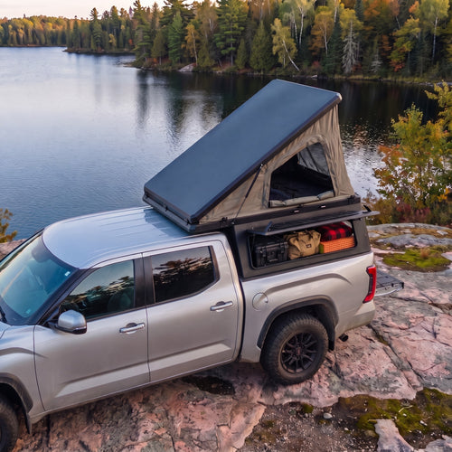 Chevrolet Colorado Single Pop-Up truck cap camper with the roof tent open beside a northern Ontario lake