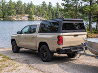 Chevy Colorado with a windowed truck cap towing an aluminum fishing boat at a boat launch