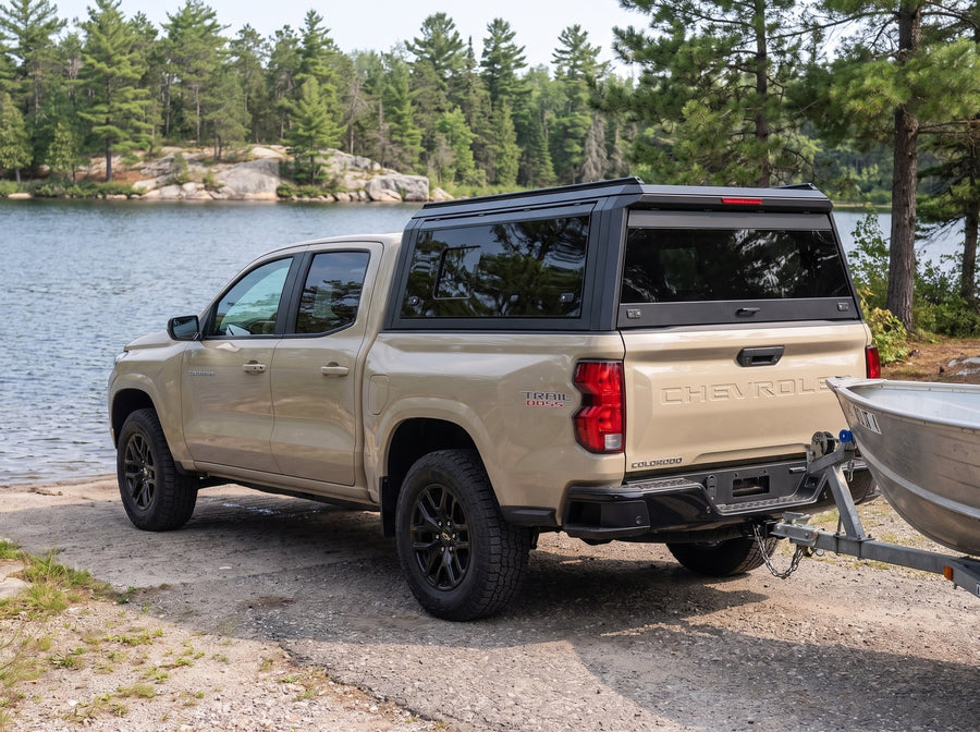 Chevy Colorado with a windowed truck cap towing an aluminum fishing boat at a boat launch