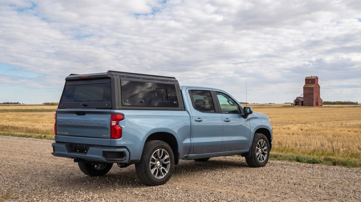 Wide view of a Chevy Silverado 1500 with a windowed aluminum truck cap parked at a gravel grid road on the Saskatchewan prairie in early autumn