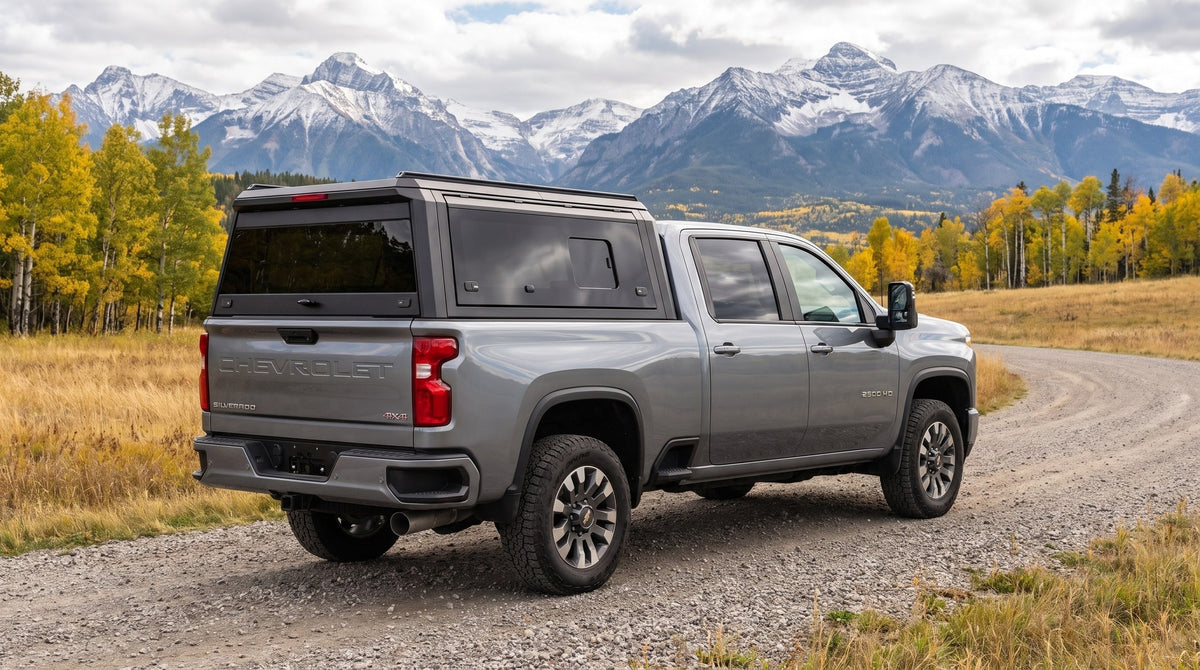 Wide view of a Chevy Silverado 2500HD 3500HD with a windowed aluminum truck cap parked at a gravel road in the Rocky Mountain foothills west of Calgary in early autumn
