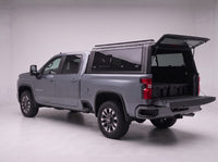 Rear door of the Chevy Silverado 2500HD 3500HD truck cap lifted open with the tailgate down and storage totes in the bed