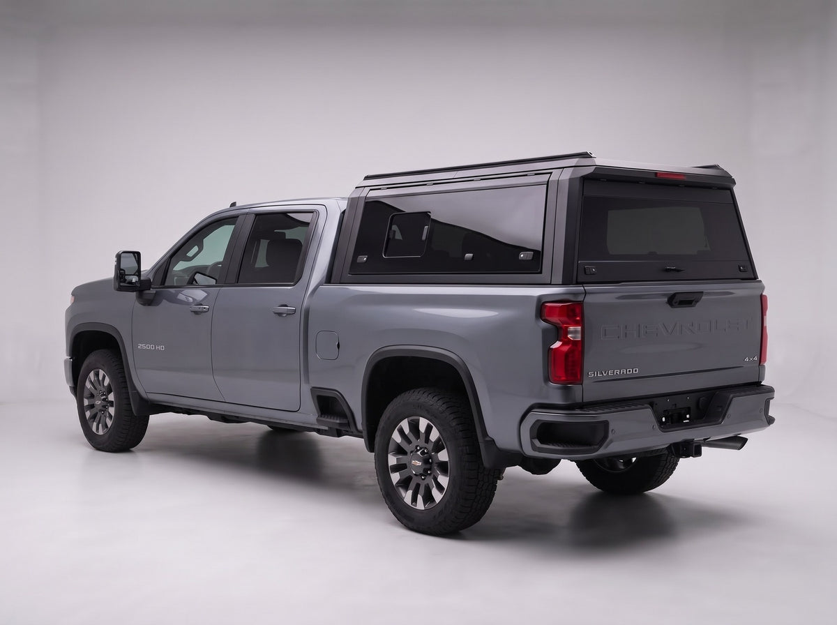Matte black aluminum truck cap with tinted windows on a Chevy Silverado 2500HD 3500HD, studio rear three-quarter view