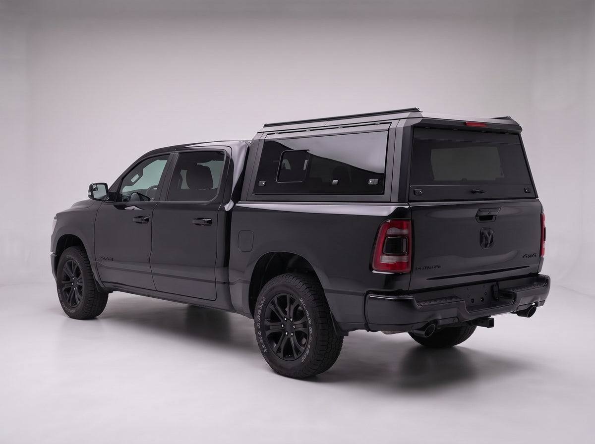 Matte black aluminum truck cap with tinted windows on a Dodge Ram 1500, studio rear three-quarter view