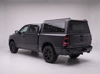 Matte black aluminum truck cap with tinted windows on a Dodge Ram 1500, studio rear three-quarter view