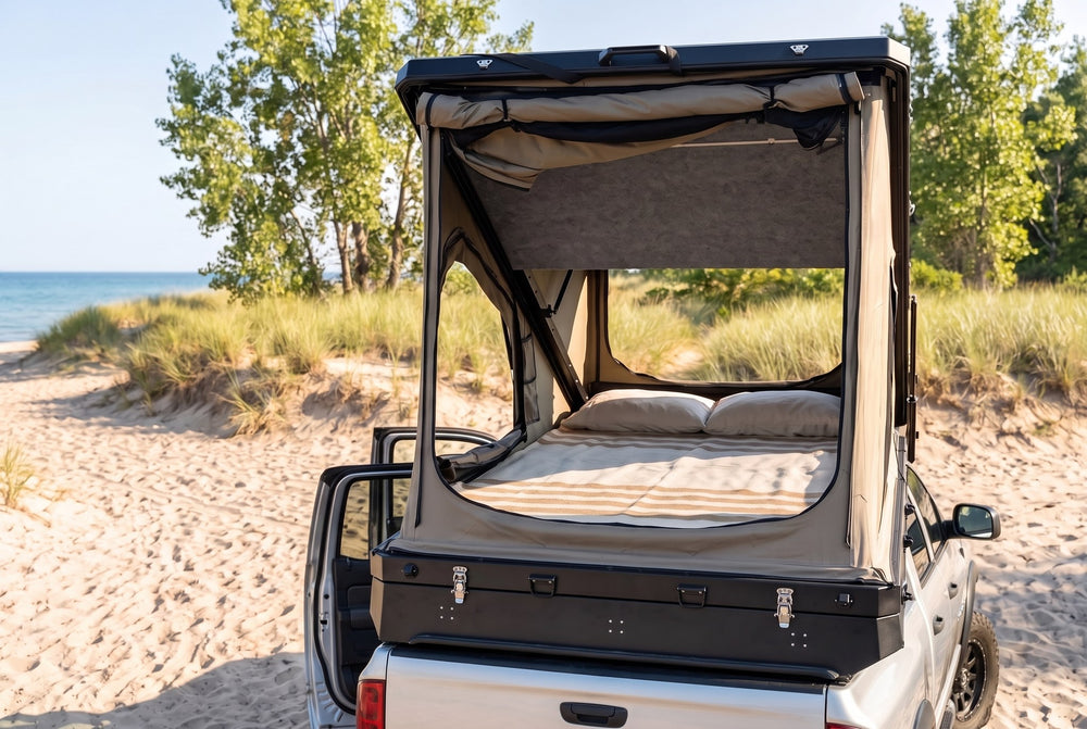 Rear view of the Dodge Ram 2500/3500 truck cap camper with the large rear tent window open and the bed made, on a Lake Huron beach