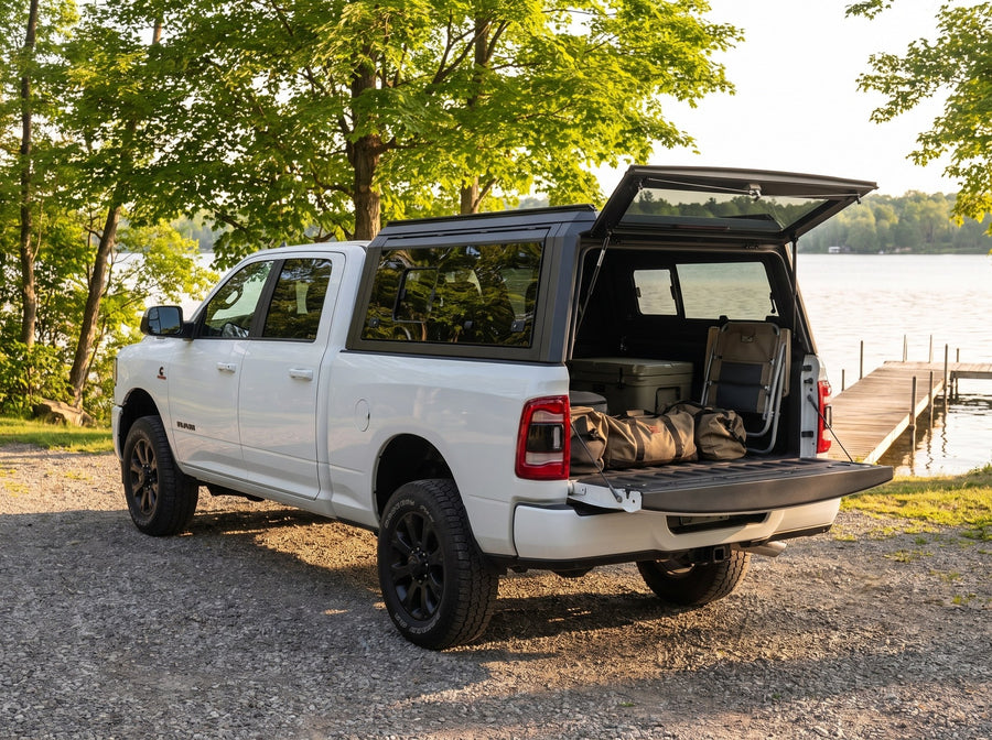 Dodge Ram 2500 3500 truck cap open at a cottage with duffel bags, a cooler and a camp chair packed in the bed