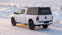 Wide view of a Dodge Ram 2500 3500 with a windowed aluminum truck cap parked at a snow-covered prairie highway in Saskatchewan in winter