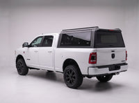 Matte black aluminum truck cap with tinted windows on a Dodge Ram 2500 3500, studio rear three-quarter view