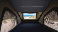 Inside the Double Pop-Up roof tent with bug-mesh windows on both sides and a beach view through the end window