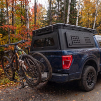 Ford F-150 canopy camper closed, rear three-quarter view showing the locking MOLLE side panel and hitch bike rack