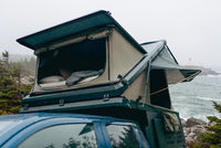 Front pop-up hatch open on the Double Pop-Up truck cap camper above a Ford F-150 cab, with the bed made inside