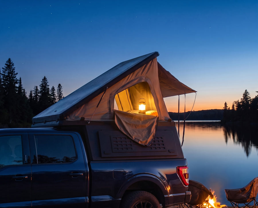 Ford F-150 pop-up camper glowing at dusk beside a northern lake with a campfire