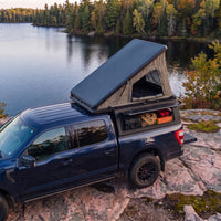 Ford F-150 Single Pop-Up truck cap camper with the roof tent open beside a northern Ontario lake