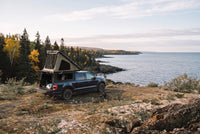 Wide view of a Ford F-150 truck camper set up above the Lake Superior shoreline in autumn