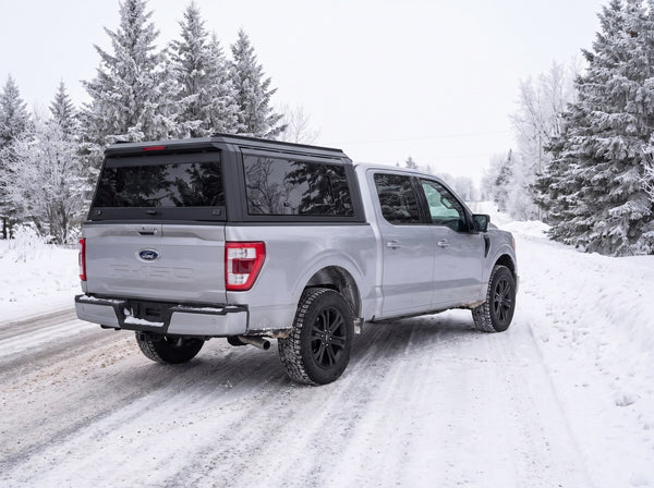 Ford F-150 with an aluminum truck cap on a winter road