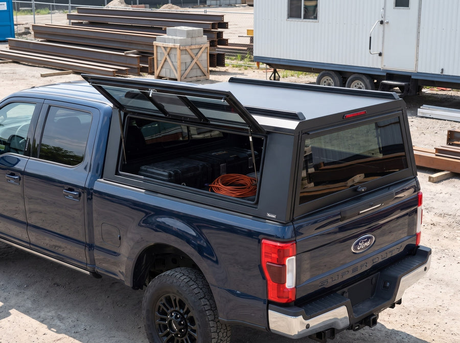 Ford F-250 F-350 Super Duty truck cap with the side window lifted open at a job site, tool cases and an extension cord inside