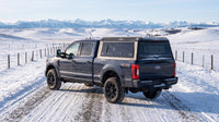 Wide view of a Ford F-250 F-350 Super Duty with a windowed aluminum truck cap parked at a snow-covered ranch road in southern Alberta in winter