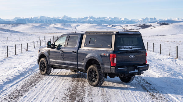 Ford Super Duty with an aluminum truck cap on a winter road