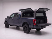 Rear door of the Ford F-250 F-350 Super Duty truck cap lifted open with the tailgate down and storage totes in the bed