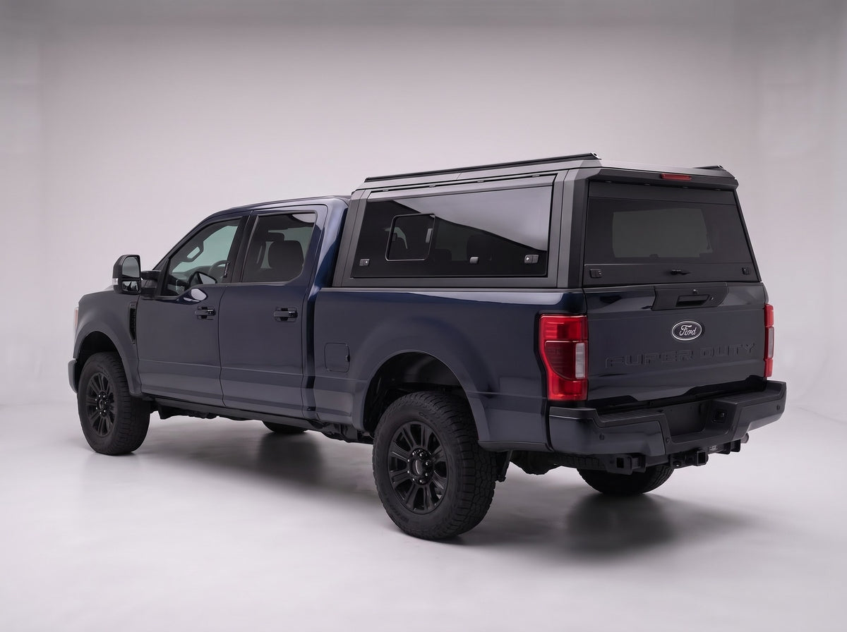 Matte black aluminum truck cap with tinted windows on a Ford F-250 F-350 Super Duty, studio rear three-quarter view
