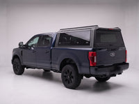 Matte black aluminum truck cap with tinted windows on a Ford F-250 F-350 Super Duty, studio rear three-quarter view