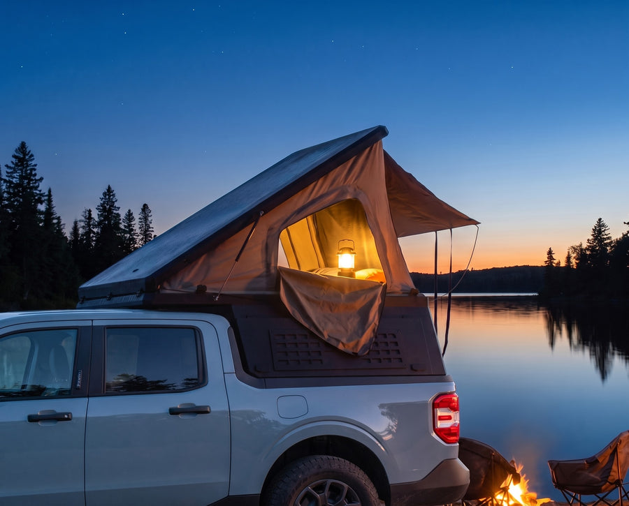 Ford Maverick pop-up camper glowing at dusk beside a northern lake with a campfire