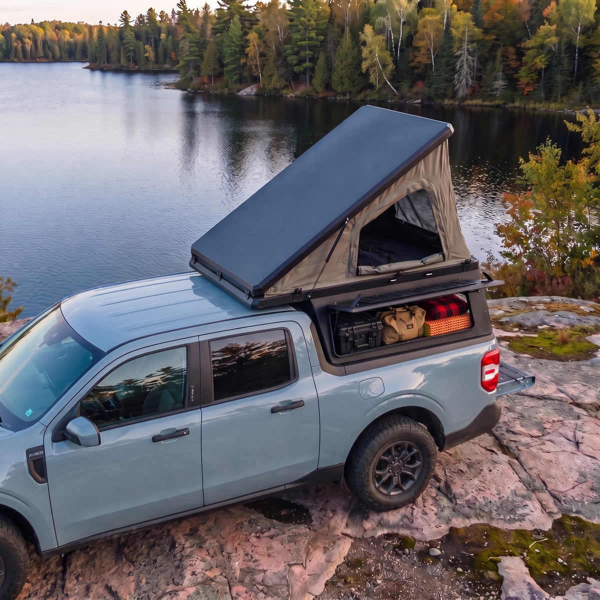 Ford Maverick Single Pop-Up truck cap camper with the roof tent open beside a northern Ontario lake