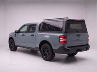 Ford Maverick truck cap with the honeycomb security guard showing through the tinted rear window, studio view