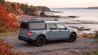Wide view of a Ford Maverick with a windowed aluminum truck cap parked at a coastal road above the Bay of Fundy