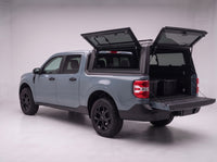 Rear door of the Ford Maverick truck cap lifted open with the tailgate down and storage totes in the bed