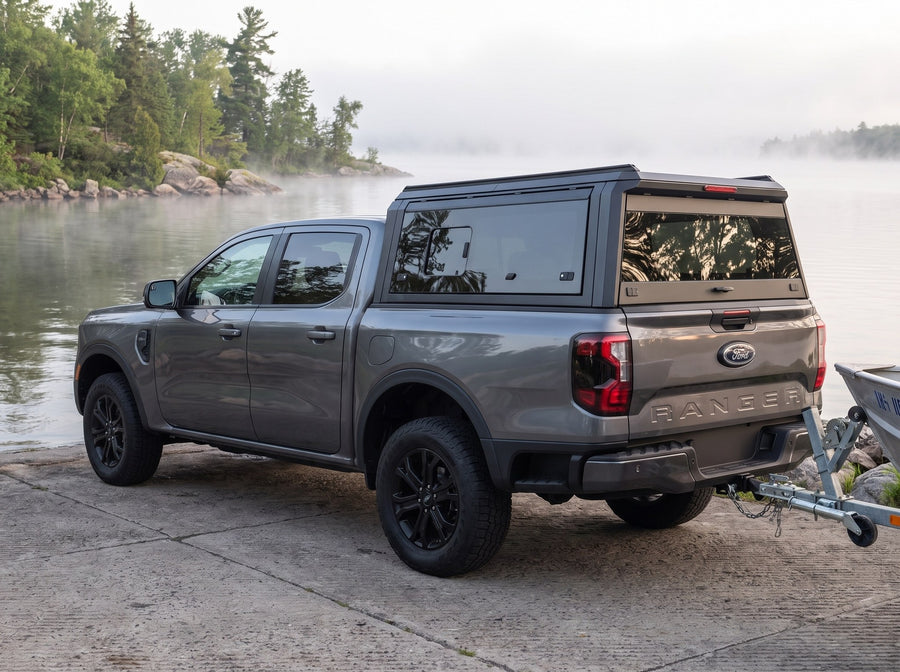 Ford Ranger with a windowed truck cap towing an aluminum fishing boat at a boat launch