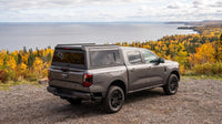 Wide view of a Ford Ranger with a windowed aluminum truck cap parked at a gravel lookout above the Lake Superior shoreline in Northern Ontario in autumn