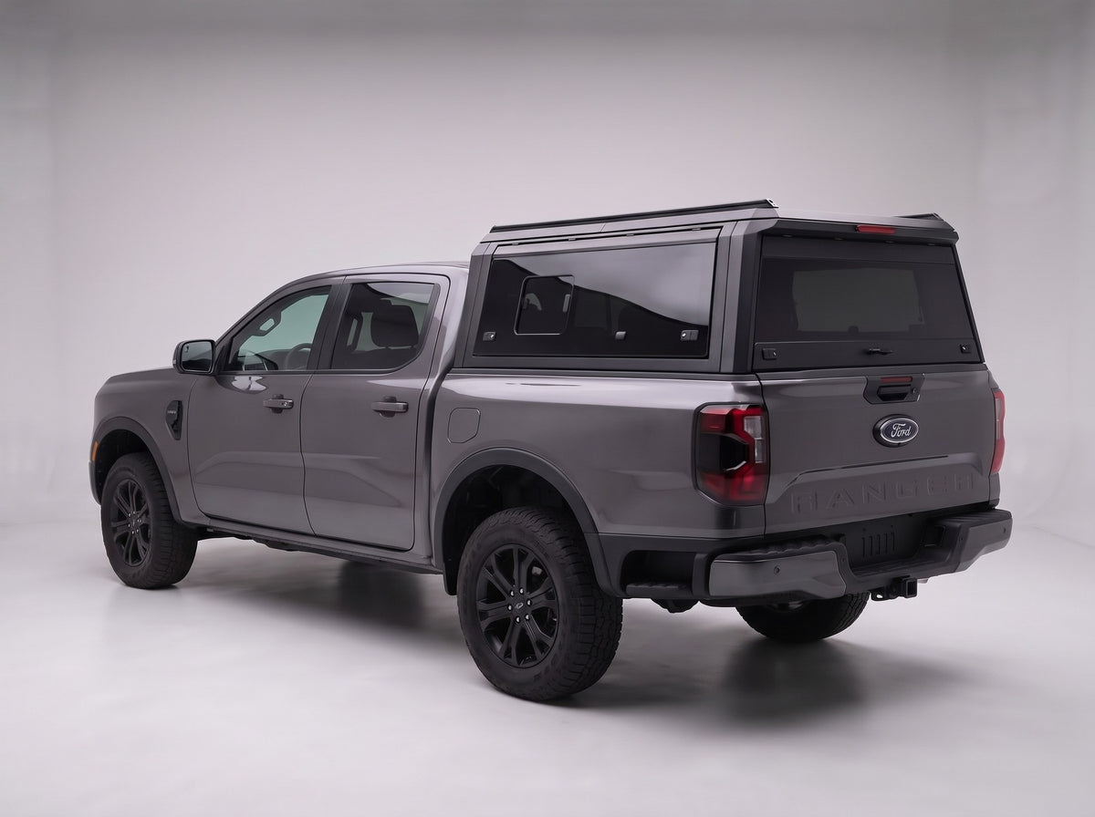 Matte black aluminum truck cap with tinted windows on a Ford Ranger, studio rear three-quarter view