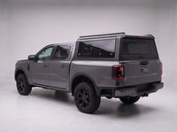 Matte black aluminum truck cap with tinted windows on a Ford Ranger, studio rear three-quarter view