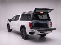 Rear door of the GMC Sierra 1500 truck cap lifted open with the tailgate down and storage totes in the bed