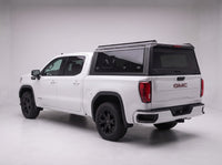 Matte black aluminum truck cap with tinted windows on a GMC Sierra 1500, studio rear three-quarter view