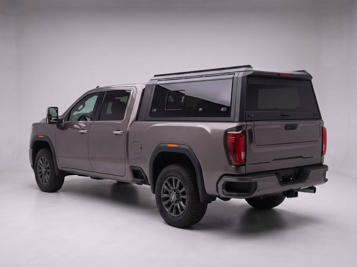 Matte black aluminum truck cap with tinted windows on a GMC Sierra 2500HD 3500HD, studio rear three-quarter view