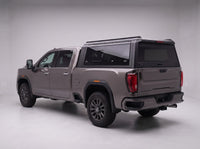 Matte black aluminum truck cap with tinted windows on a GMC Sierra 2500HD 3500HD, studio rear three-quarter view