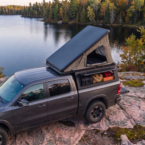 Ram 1500 Single Pop-Up truck cap camper with the roof tent open beside a northern Ontario lake