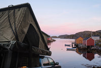 Side of the open roof tent on a Ram 1500, overlooking a Newfoundland fishing cove at dawn (the side awning shown is not included)