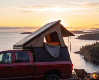 Dodge Ram 2500/3500 pop-up truck cap camper with the roof tent open at sunset over Lake Superior