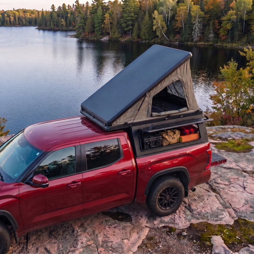 Dodge Ram 2500/3500 Single Pop-Up truck cap camper with the roof tent open beside a northern Ontario lake