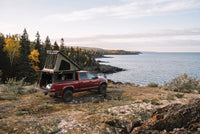 Wide view of a Dodge Ram 2500/3500 truck camper set up above the Lake Superior shoreline in autumn