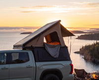 Toyota Tacoma pop-up truck cap camper with the roof tent open at sunset over Lake Superior