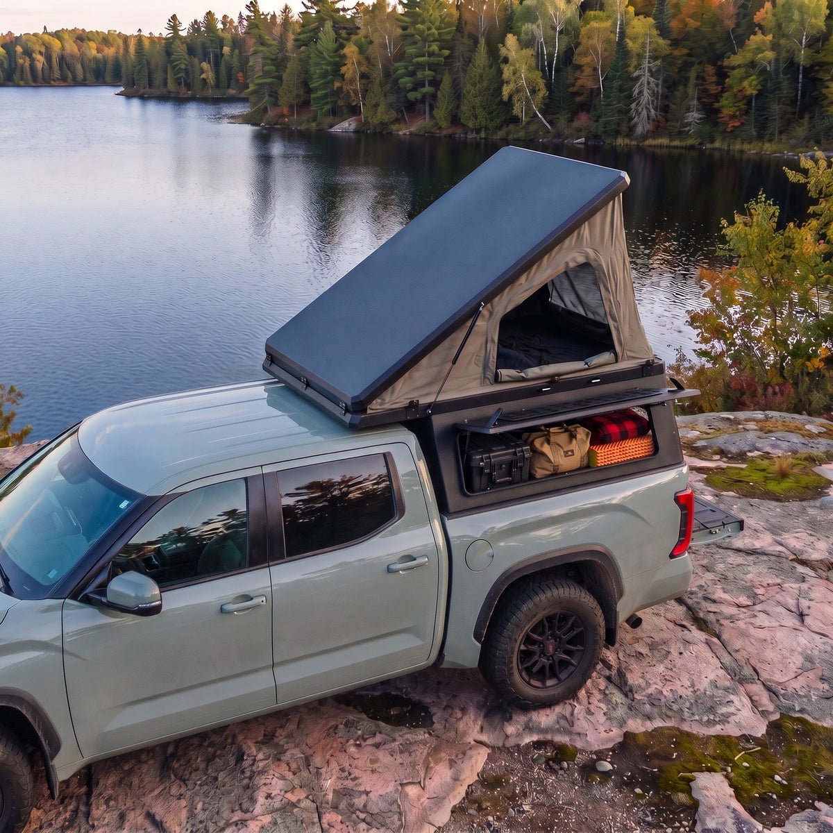 Toyota Tacoma Single Pop-Up truck cap camper with the roof tent open beside a northern Ontario lake